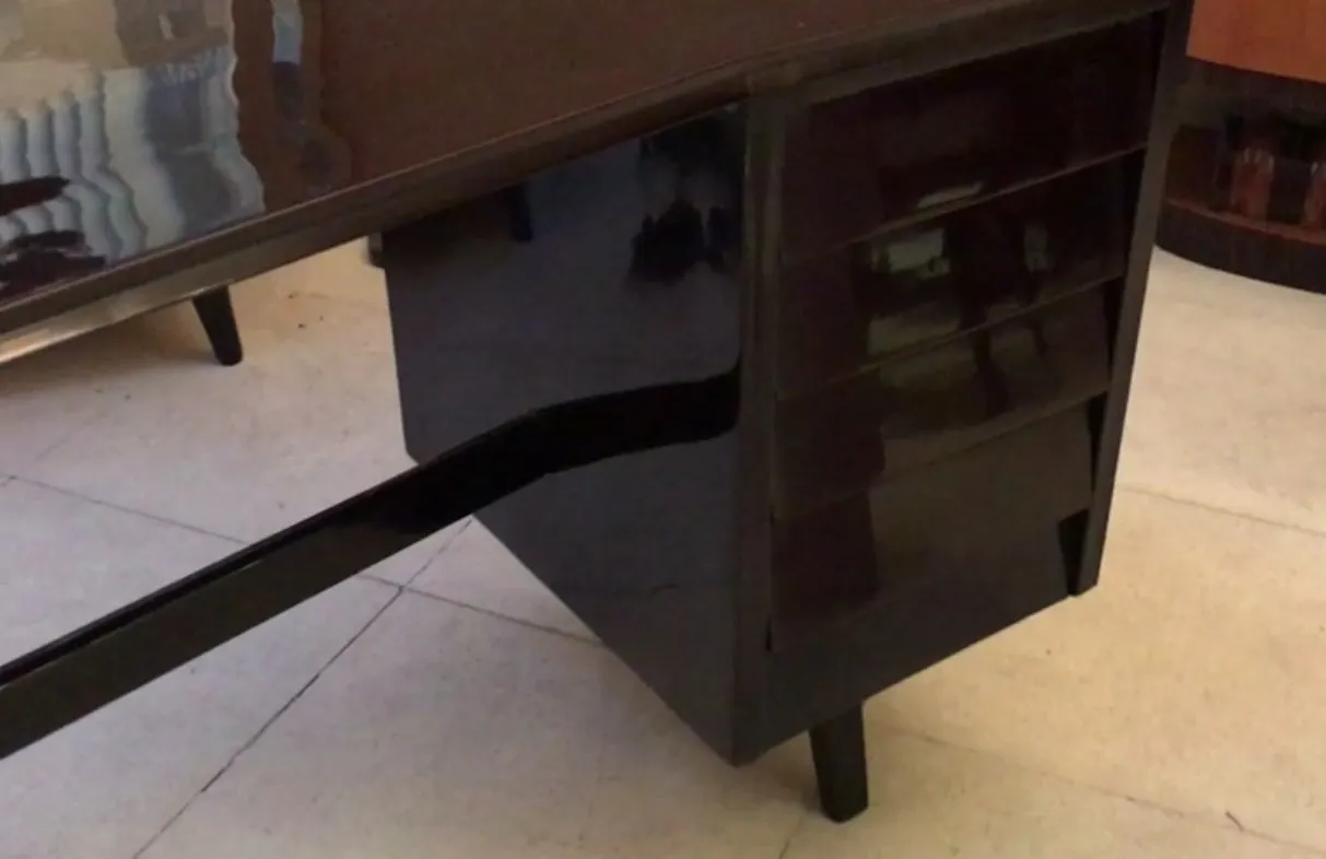 Antiker Schreibtisch mit glänzender Oberfläche und subtilen Griffen in der Umgebung.