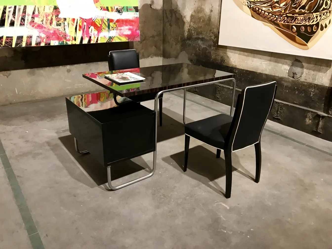 Bureau ancien dans un cadre artistique avec des chaises noires.