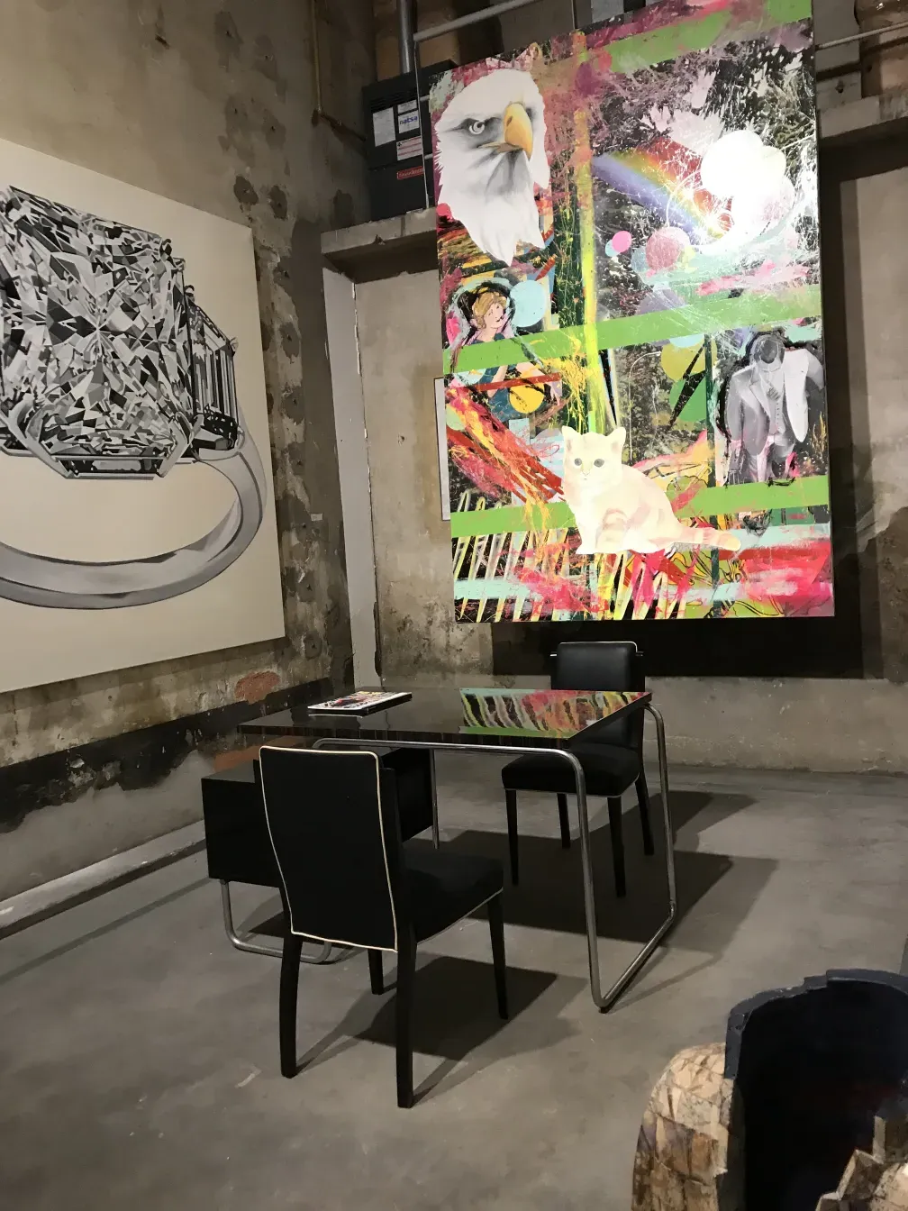 Antique desk with colorful art and black chairs