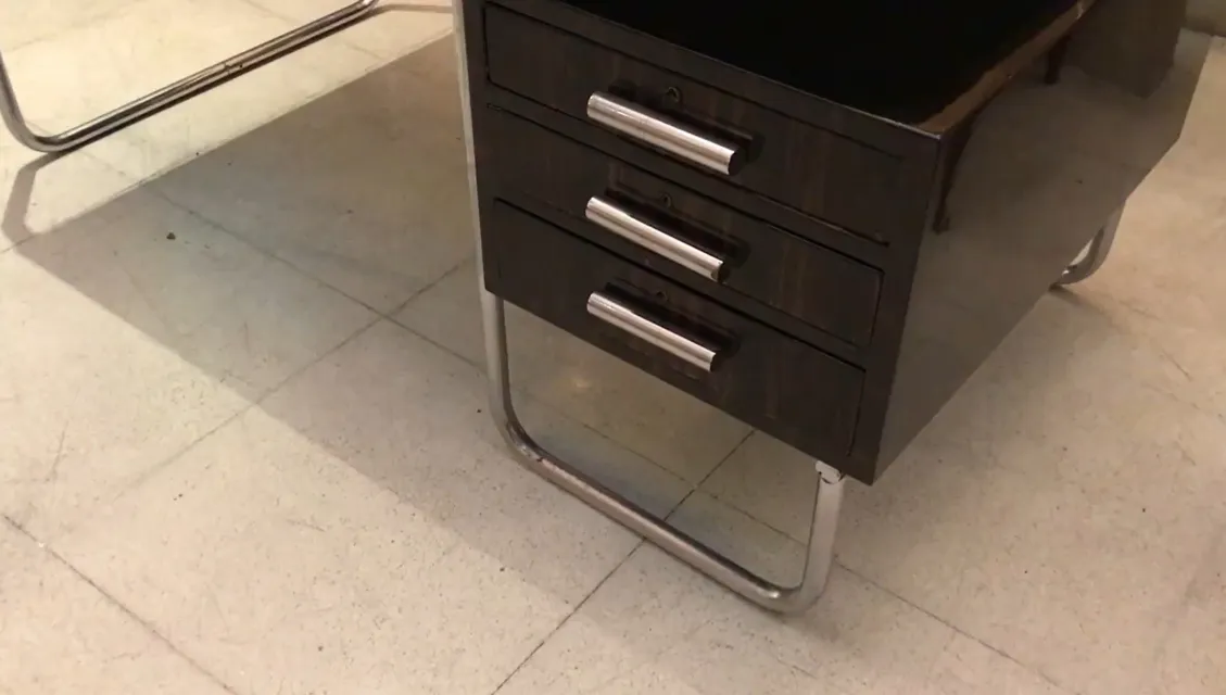 Bureau ancien avec trois tiroirs dans un cadre moderne.