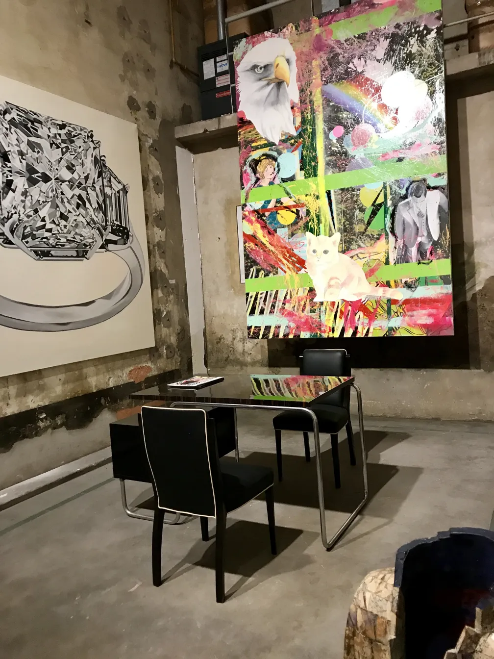 Alter Schreibtisch mit elegantem Design und schwarzen Stühlen in künstlerischer Umgebung.