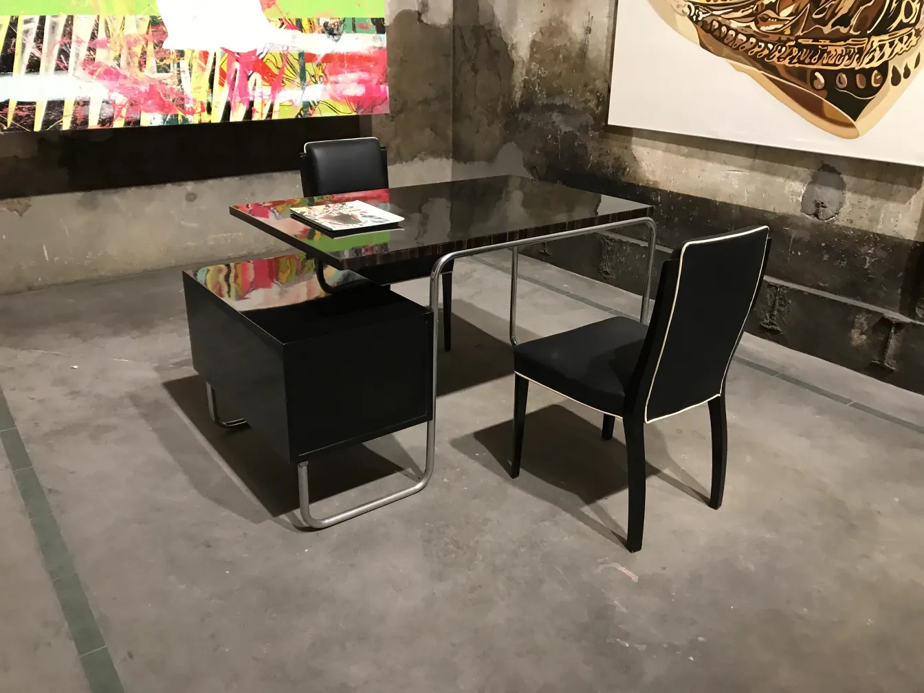 escritorio antigo preto com cadeiras em uma galeria de arte