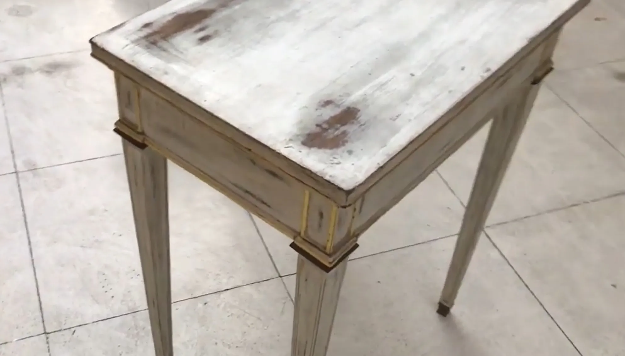 escritorio antigo branco com pernas claras e detalhes em dourado, em fundo claro.