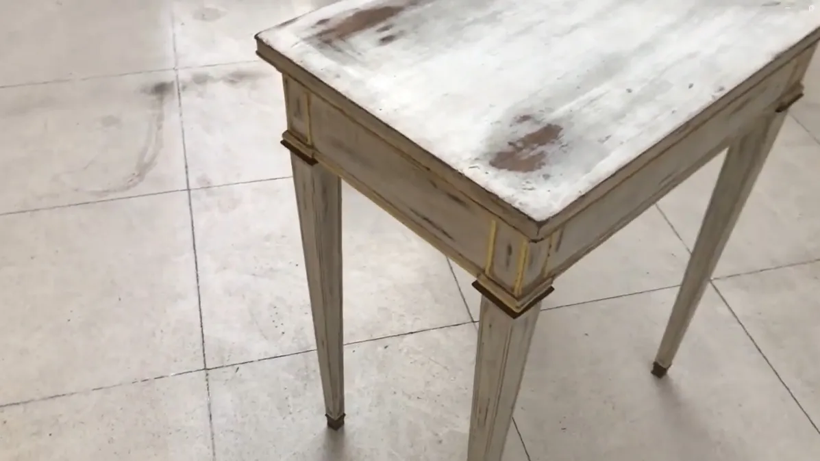 Scrivania antica bianca con gambe sottili in un ambiente luminoso.