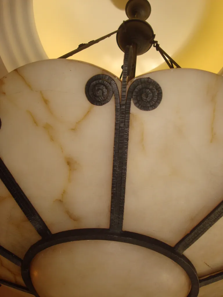 Lámpara de techo antigua con un diseño elaborado y elegante, ubicada en un ambiente cálido.