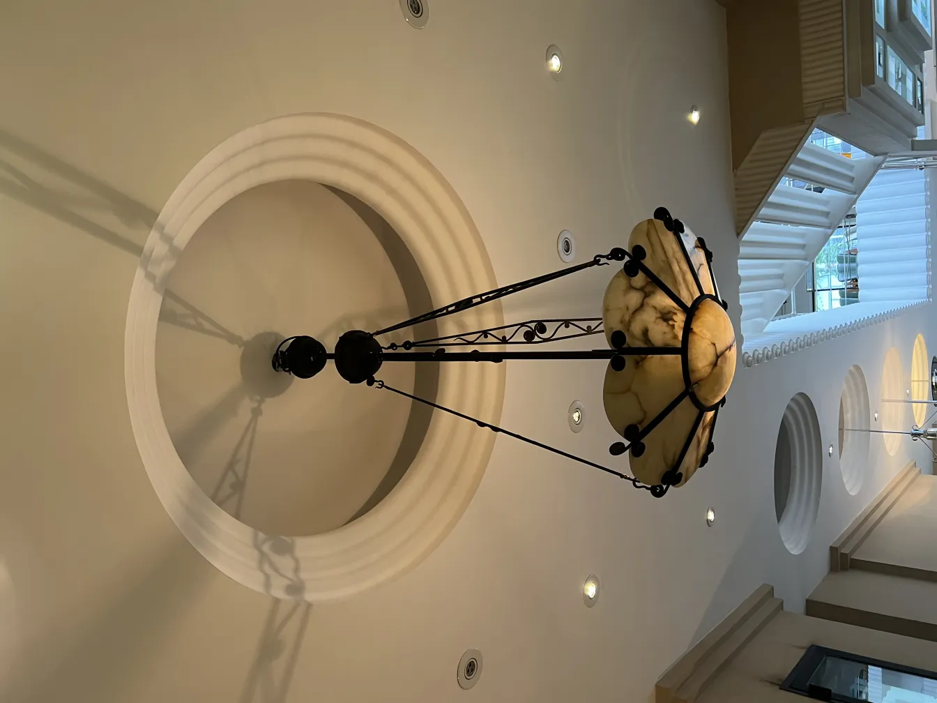 Lâmpada de teto antiga com cúpula de mármore em fundo claro.