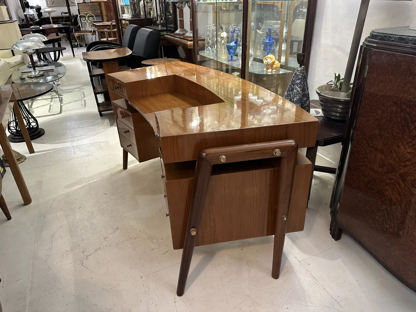 Scrivania antica con superficie lucida e gambe in legno in un negozio di antiquariato.