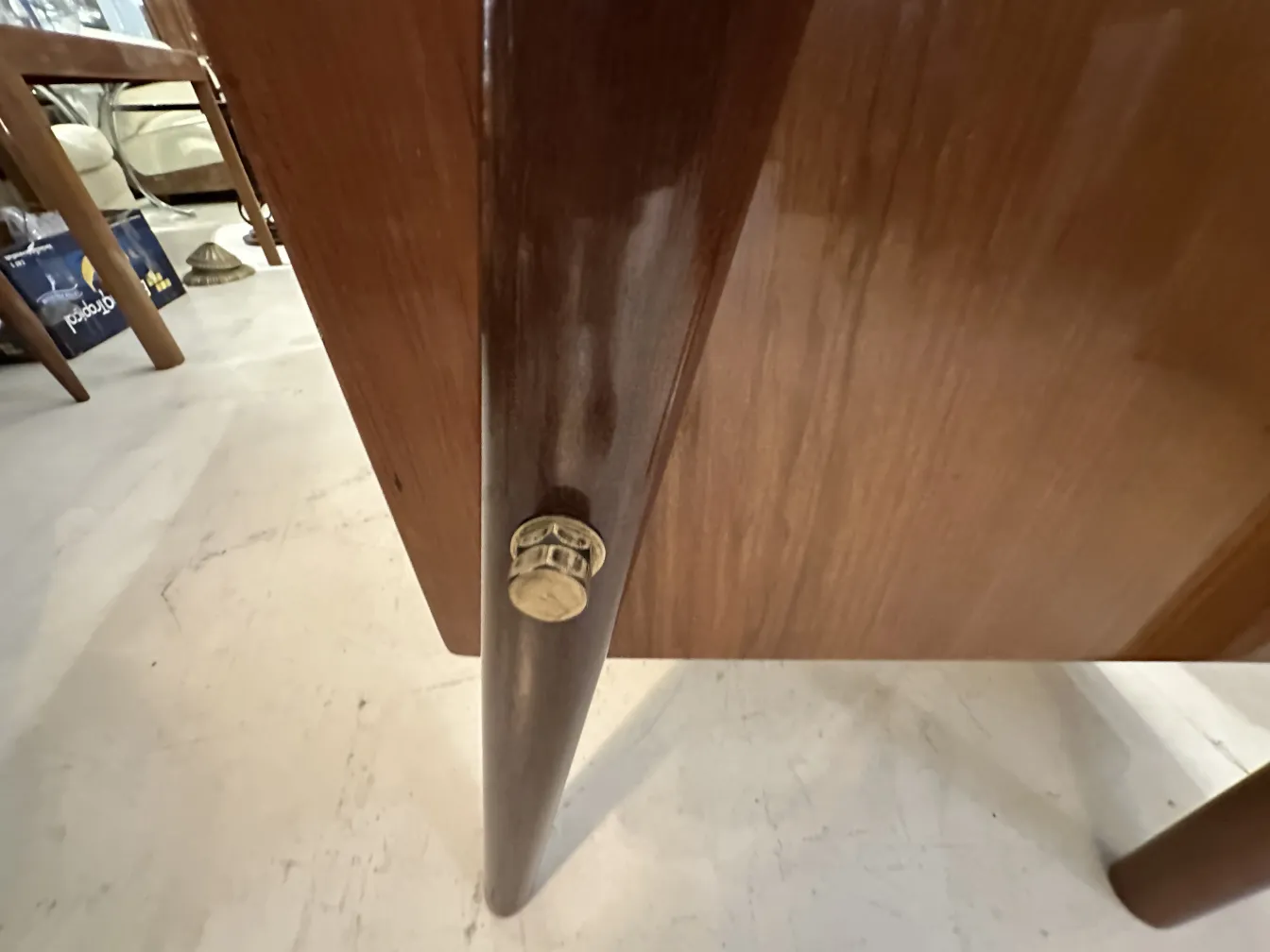 View of the leg of an antique desk with wooden finish and fittings.