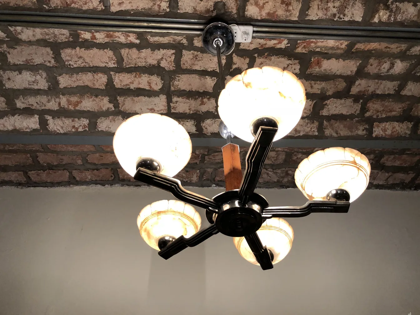 古いハンギングランプが四つの電球で空間を照らしています。むき出しのレンガの天井。
