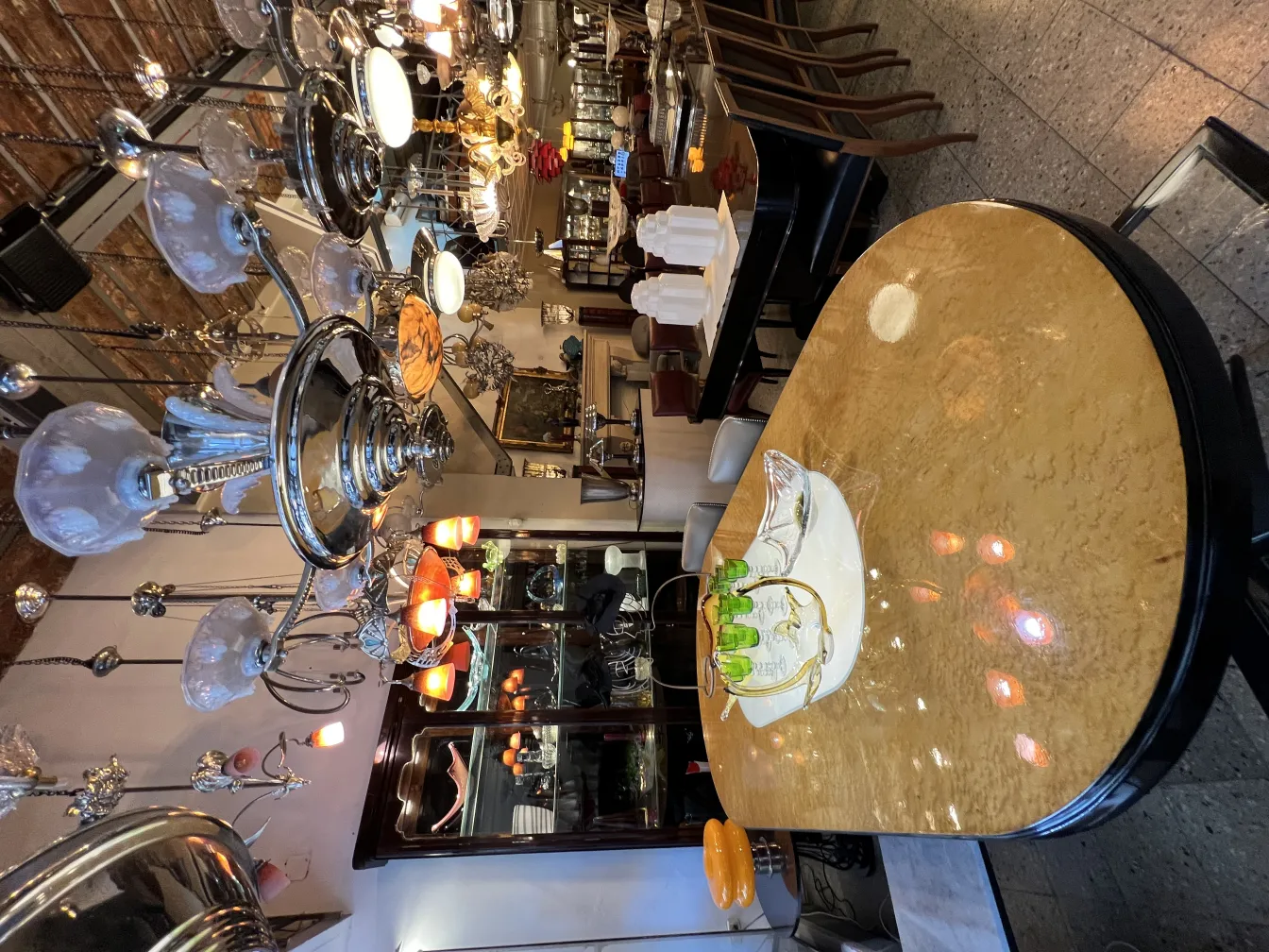 Antique hanging lamp with elaborate details in an elegant setting, accompanied by a shiny table.