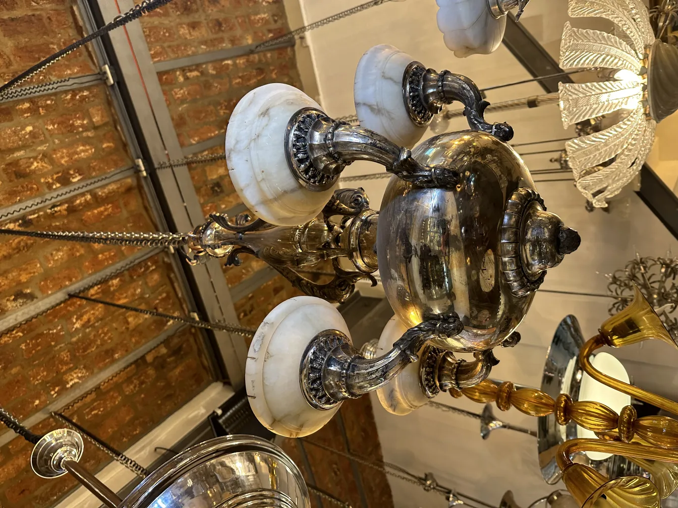 Lampada a sospensione antica con base in metallo e paralumi in marmo in un contesto di antiquariato.