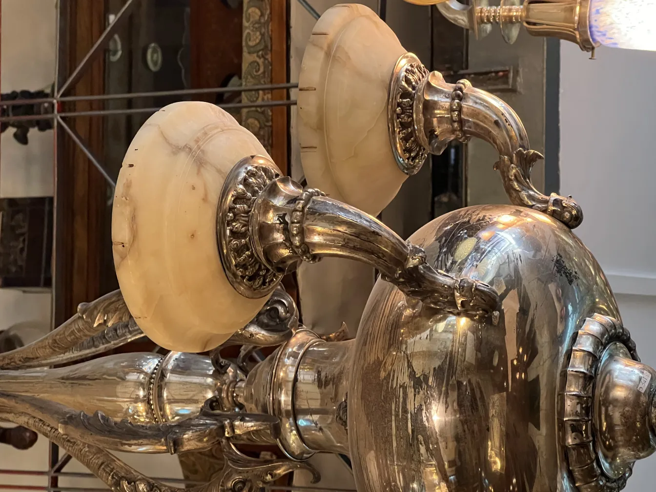 Lâmpada de teto antiga com elegantes braços curvados iluminando um ambiente clássico.