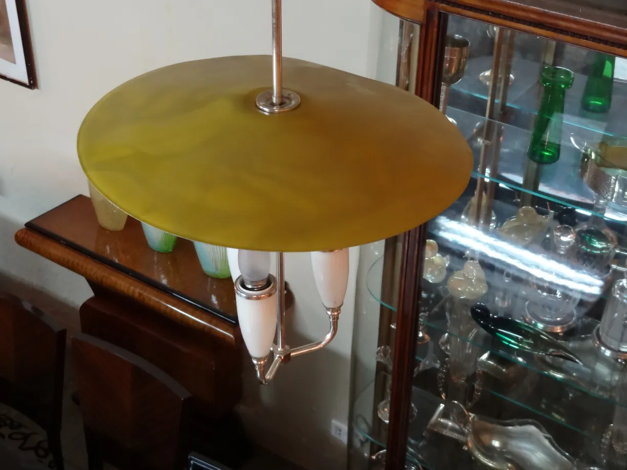 Lustre antique avec disque jaune et bras blancs. Ambiance chaleureuse avec des meubles en bois.