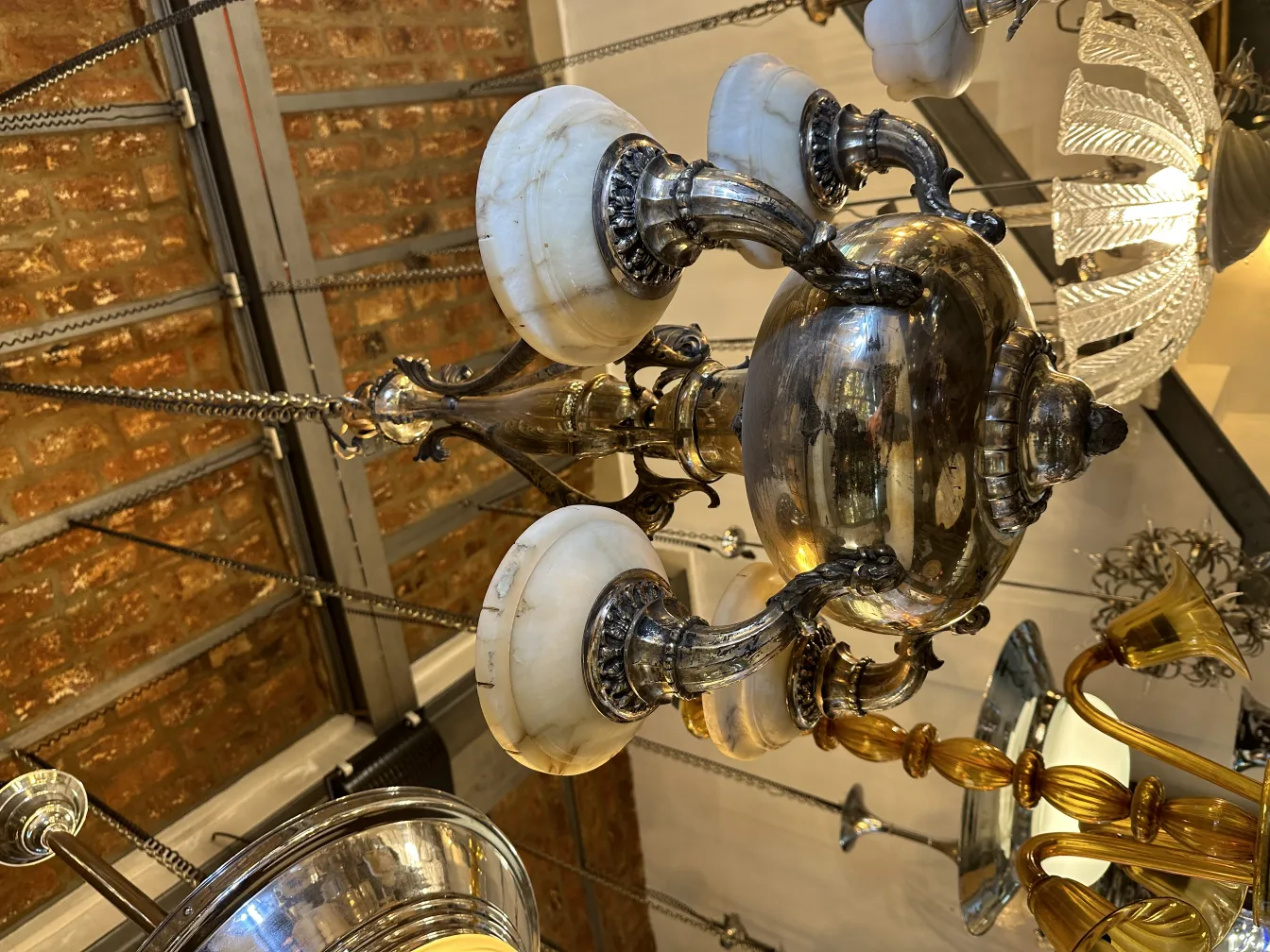 Lustre ancien avec bras ornés et teintes claires.