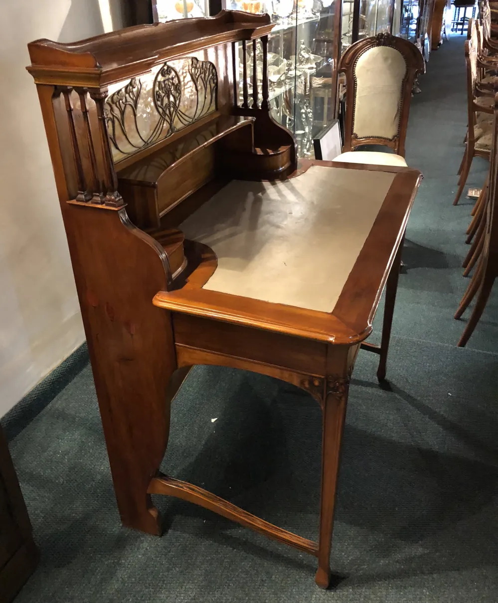 escritorio antiguo de madera con detalles en la parte trasera y superficie clara, en un ambiente clásico