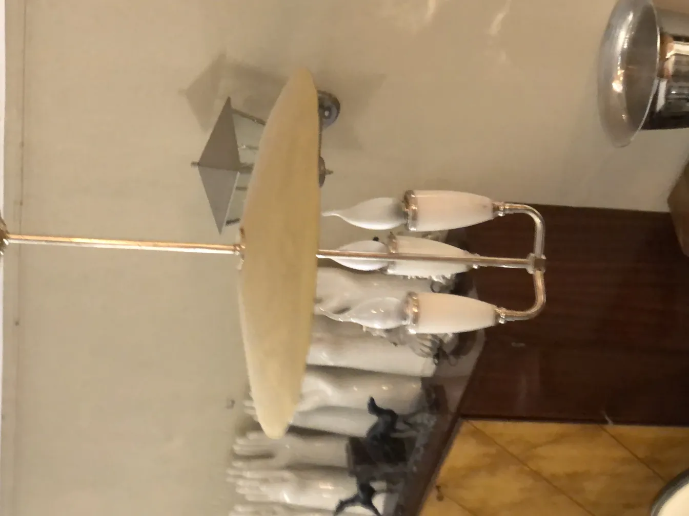 Lâmpada de teto antiga com três luzes brancas em um ambiente clássico.