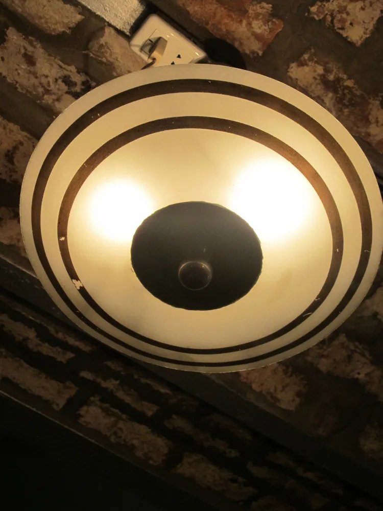 Lustre antique avec un design circulaire et des détails noir et blanc, ambiance chaleureuse.