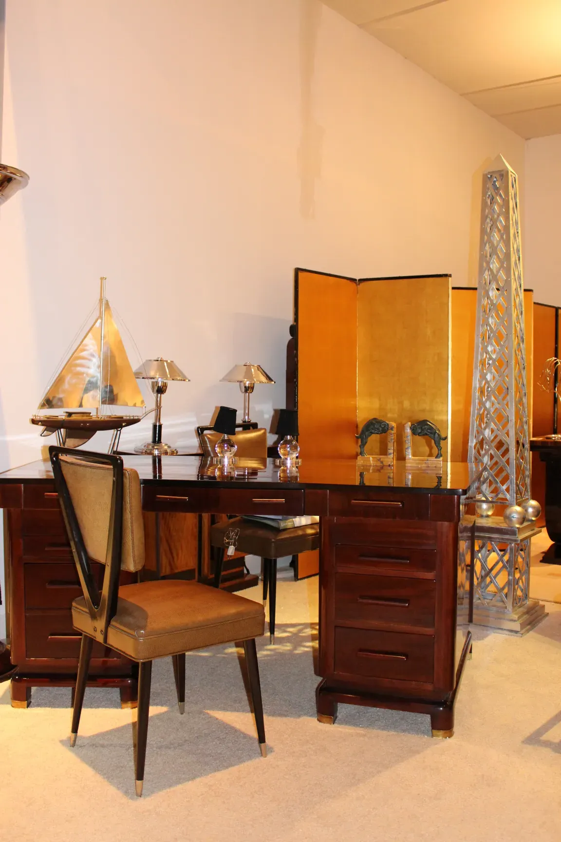 Bureau ancien en bois avec lampes et chaises en arrière-plan.