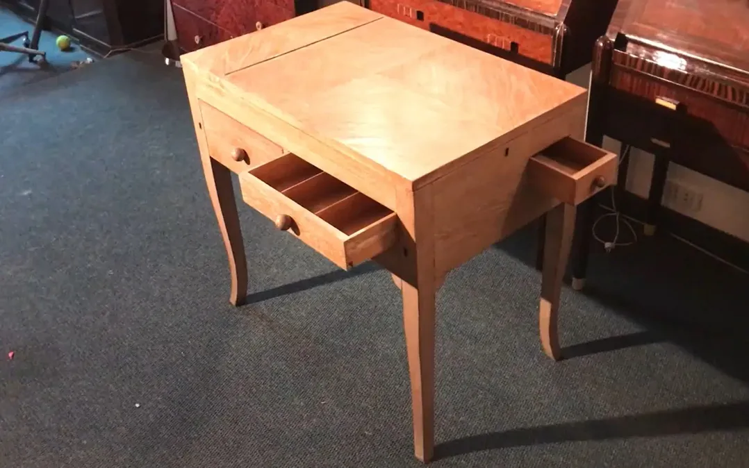 Antiker Schreibtisch aus hellem Holz mit zwei sichtbaren Schubladen.