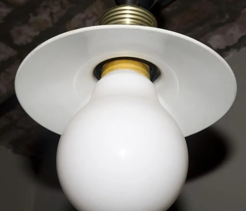 Purana latakta hua deepak safed bulb aur sunehri base ke sath