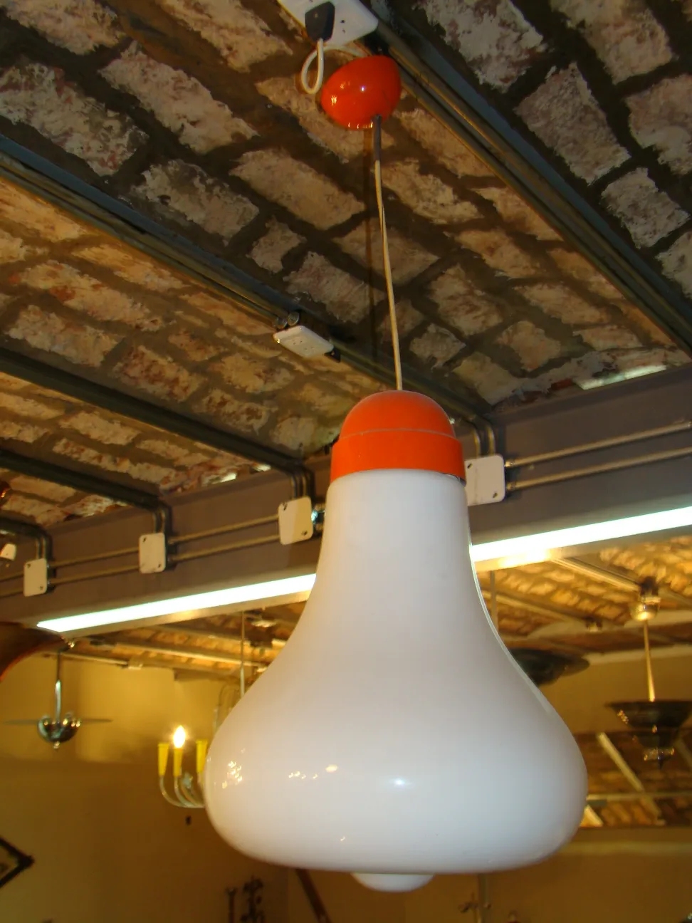 Antike weiße Hängelampe mit orangen Details in rustikalem Ambiente