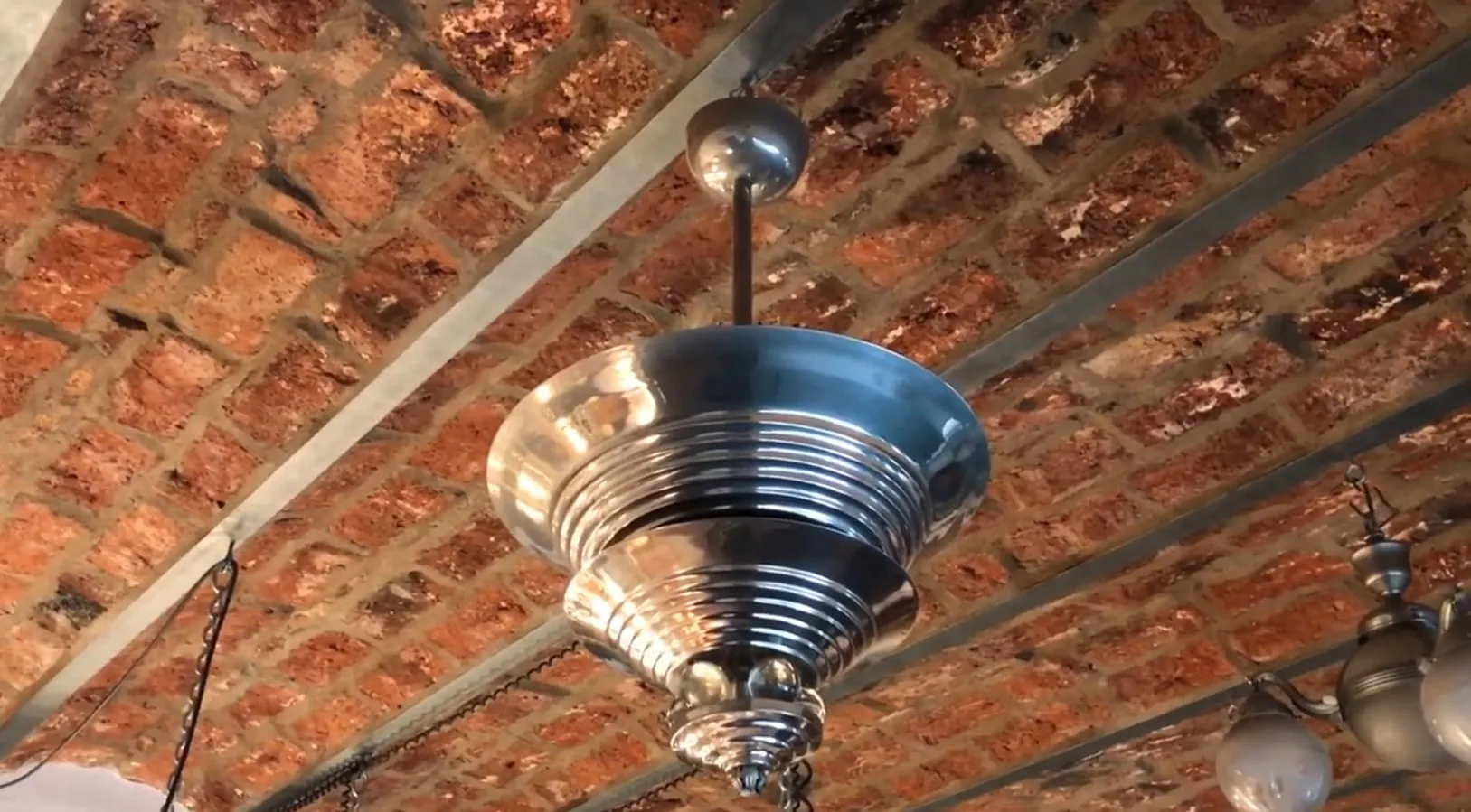 Lámpara de techo antigua con brillo metálico en un entorno rústico.