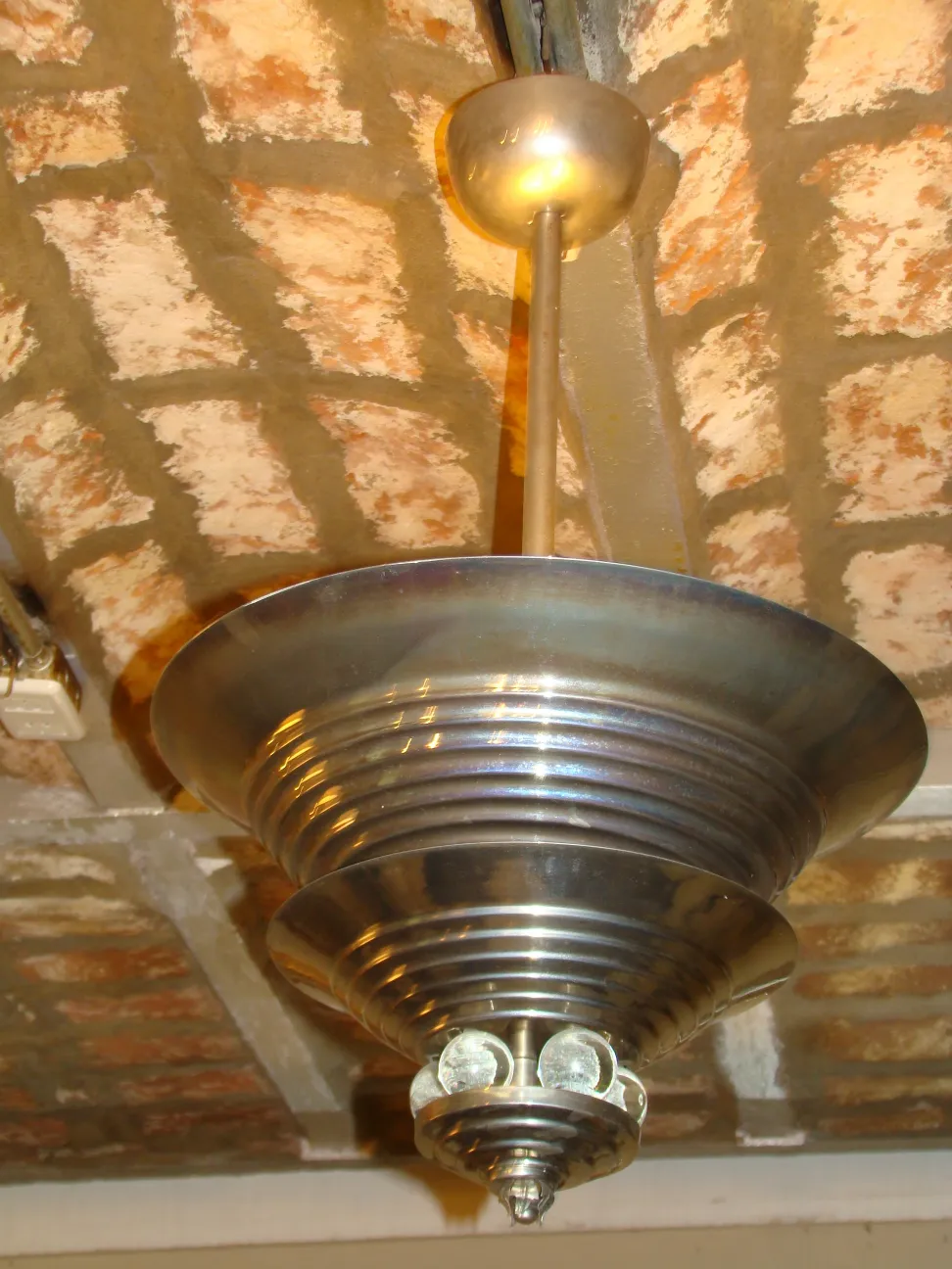 Lampada a sospensione antica con un nuovo design in metallo, sospesa in un ambiente rustico.