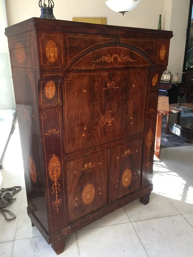 Escritorio antigo com detalhes intrincados em madeira, ambiente acolhedor.