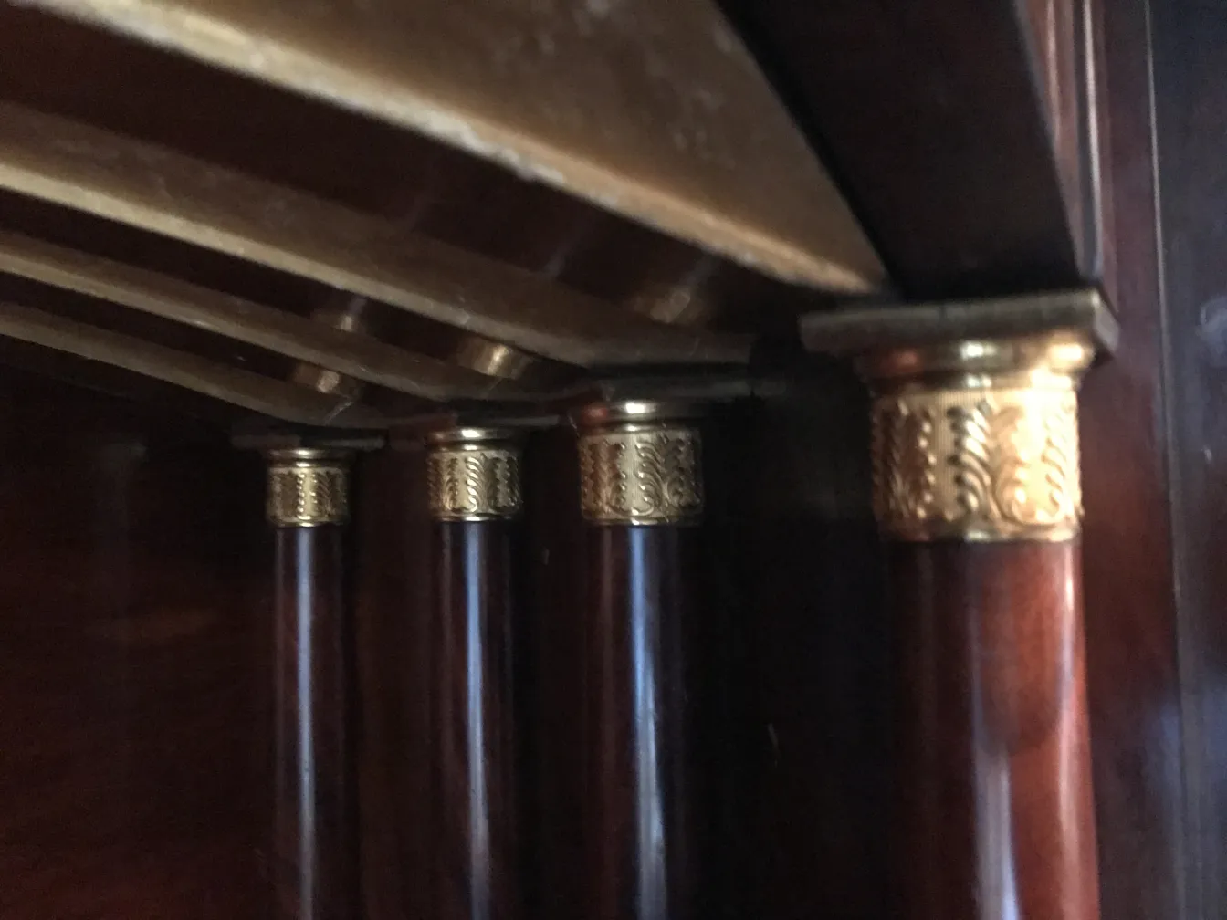 Escritorio antiguo con patas de madera y detalles dorados en la base.