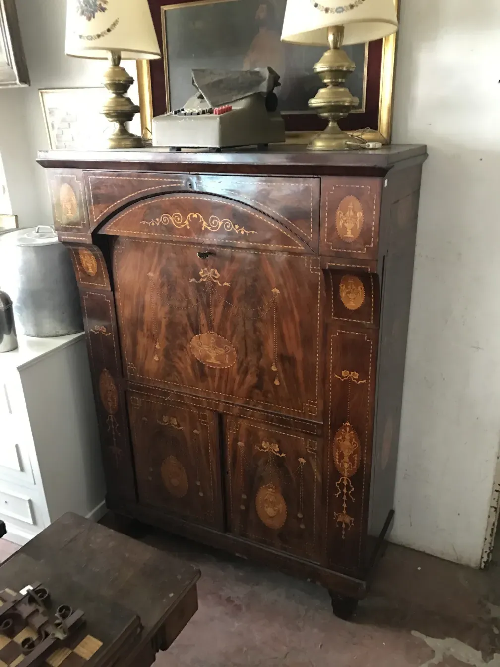 Escritorio antiguo de madera con decoraciones detalladas. Incluye lámparas y un ambiente clásico.