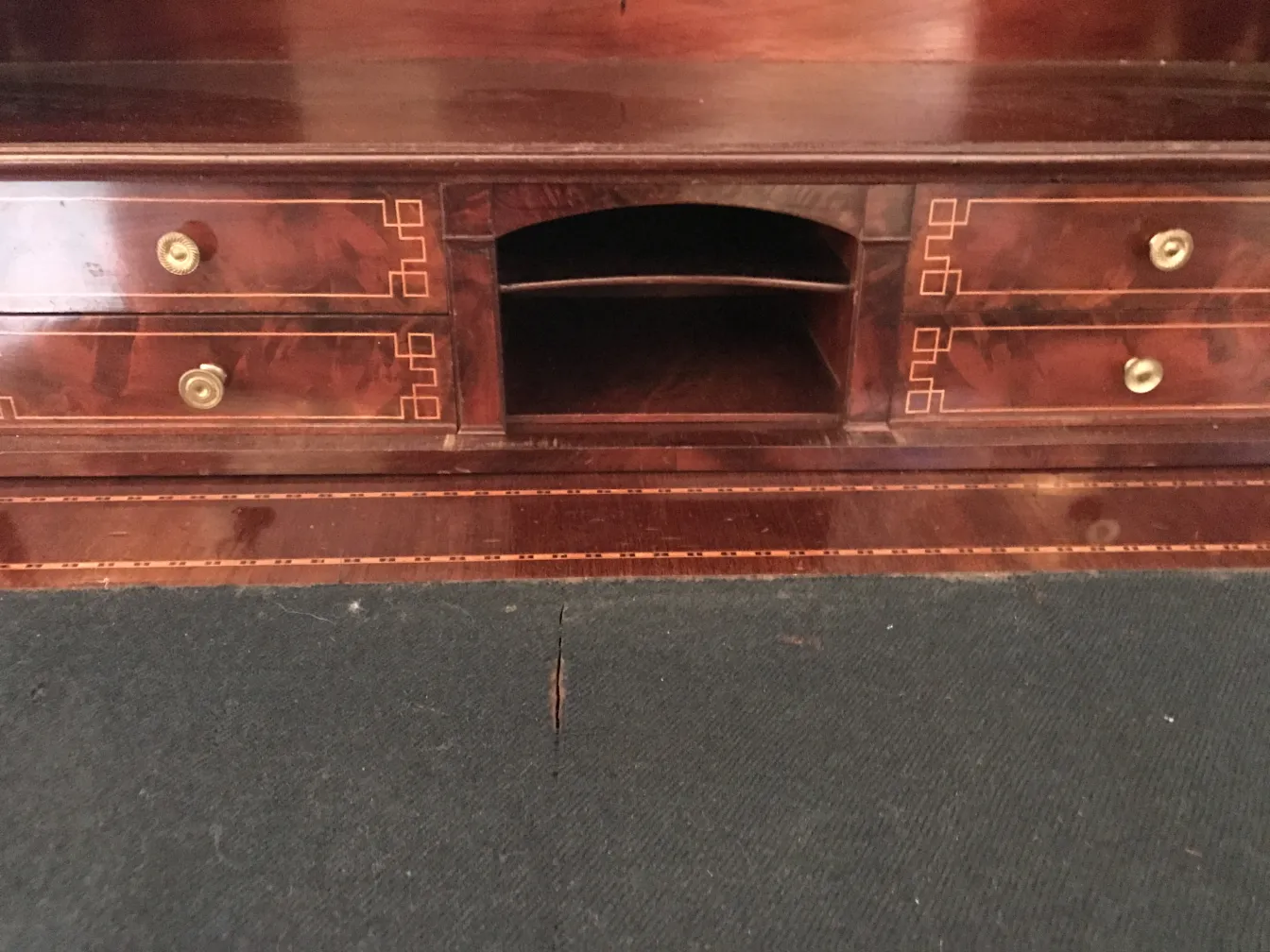 Escritorio antiguo de madera oscura con dos cajones visibles y un espacio medio abierto.