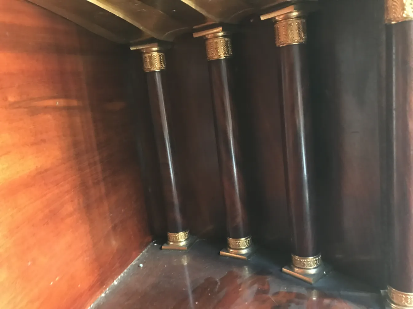 Blick auf einen antiken Schreibtisch mit Bronzebeinen und dunklem Holz.