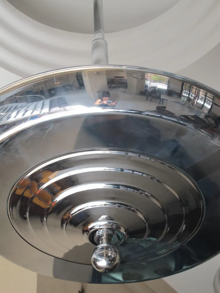 Lampada a sospensione antica con superficie riflettente, design classico.