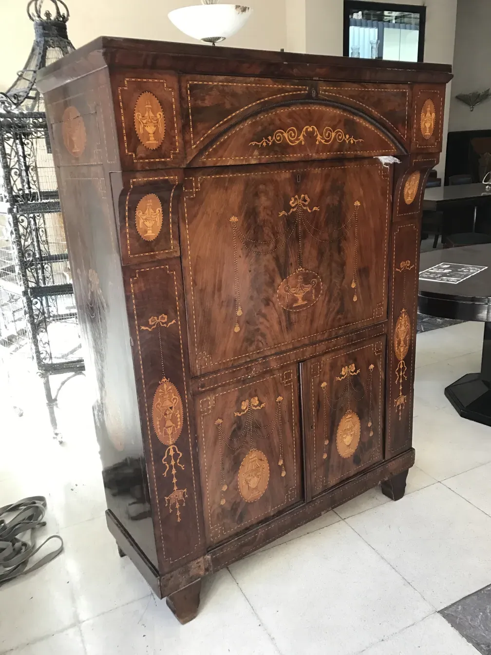 Escritorio antiguo de madera con decoraciones en el frente, en un ambiente moderno.