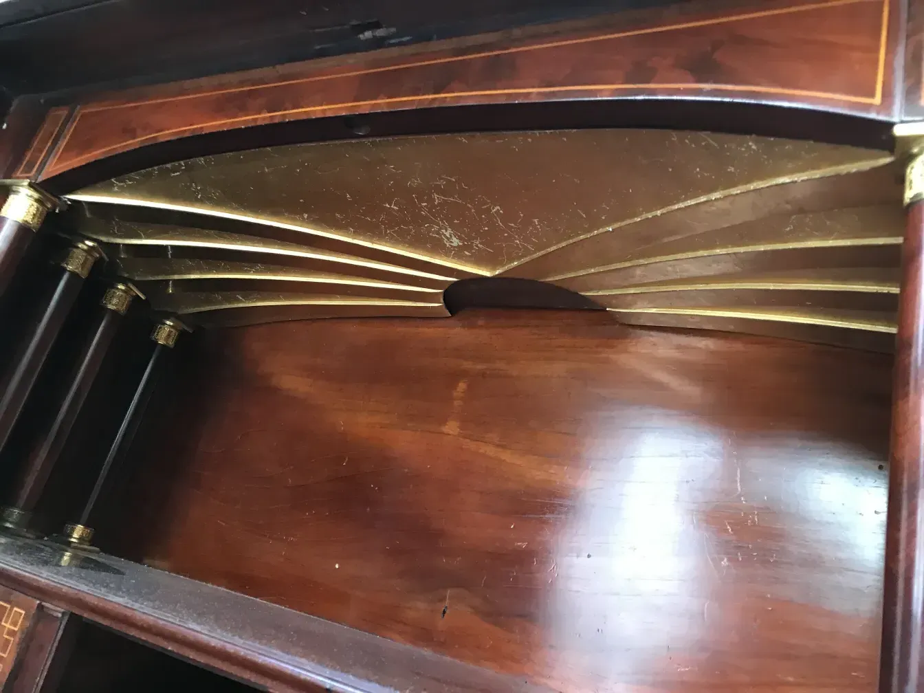 Detail eines antiken Schreibtisches mit goldenen Verzierungen.