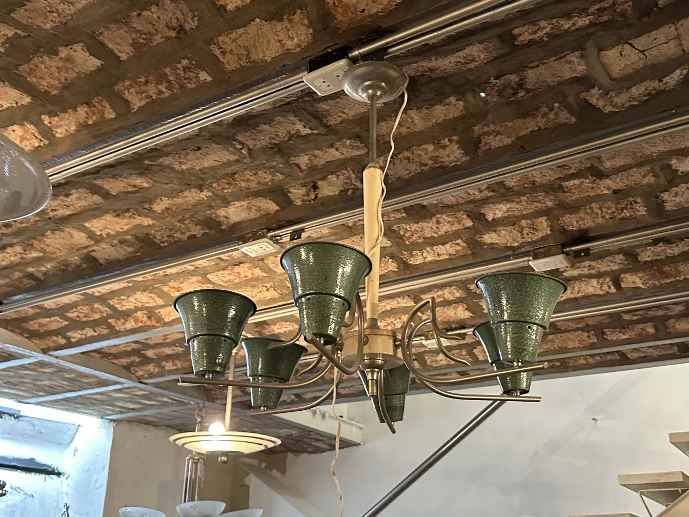 Lámpara de techo antigua con sombras verdes en ambiente rústico.