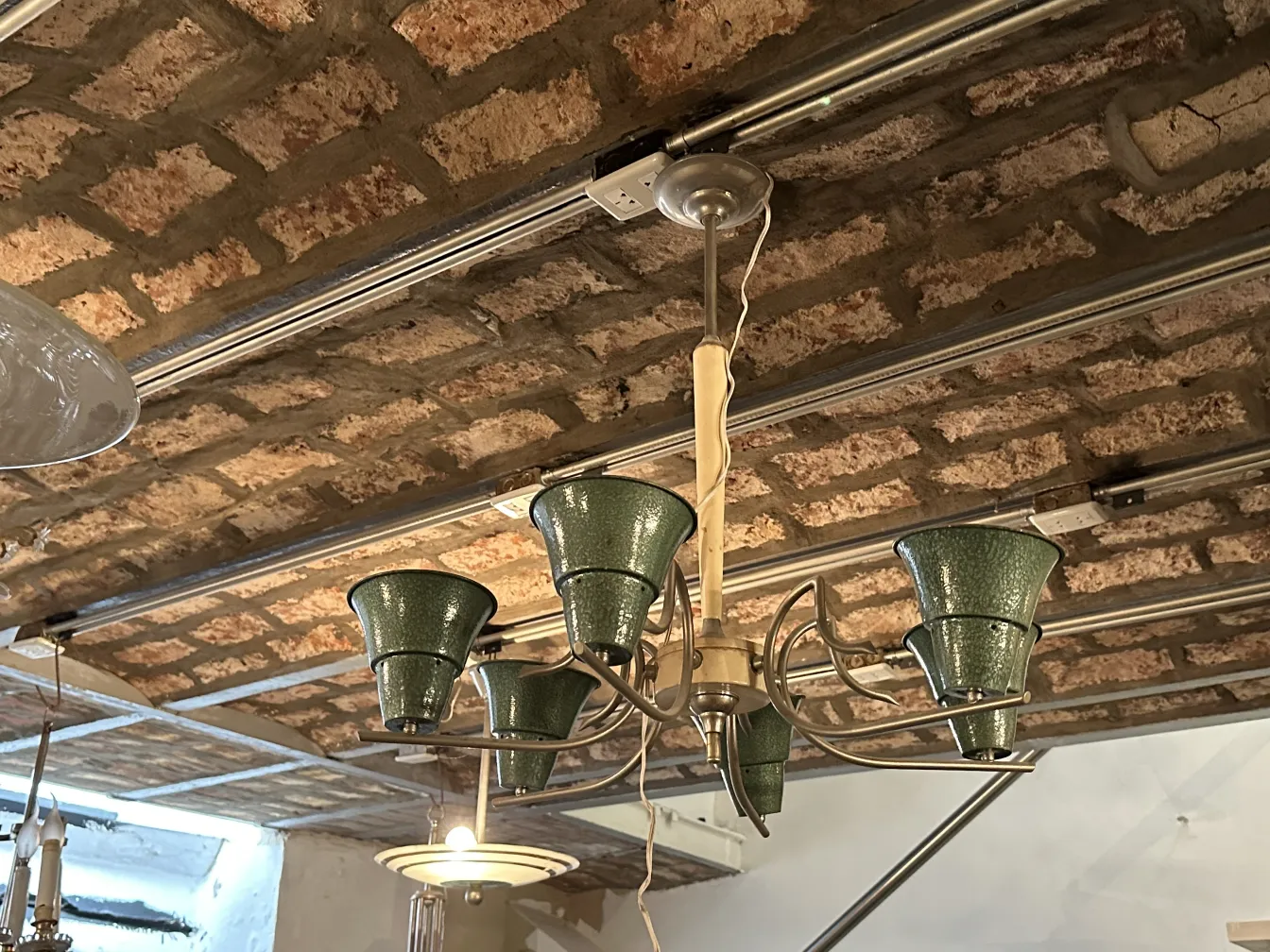 Lámpara de techo antigua con pantallas verdes en un ambiente rústico.