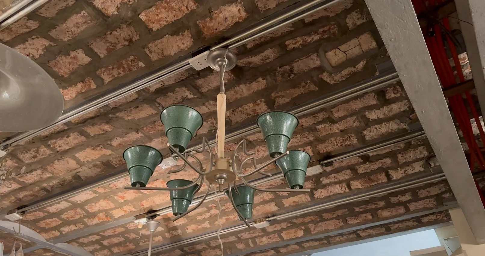 Lampada a sospensione antica con sei paralumi verdi, atmosfera rustica.