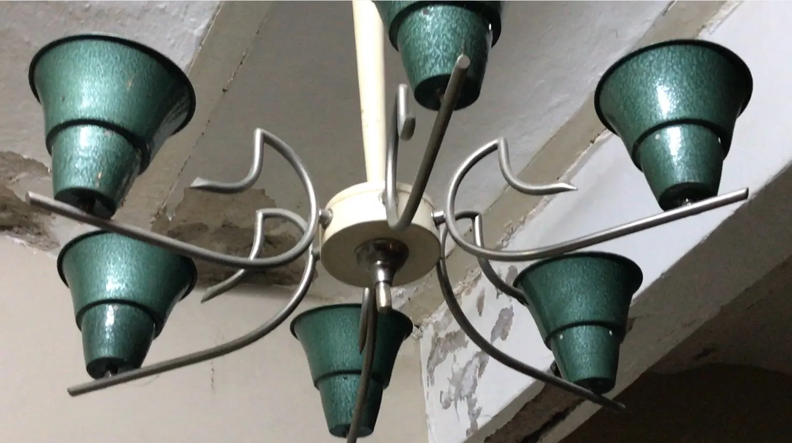 Lustre ancien avec des détails verts sur fond neutre.