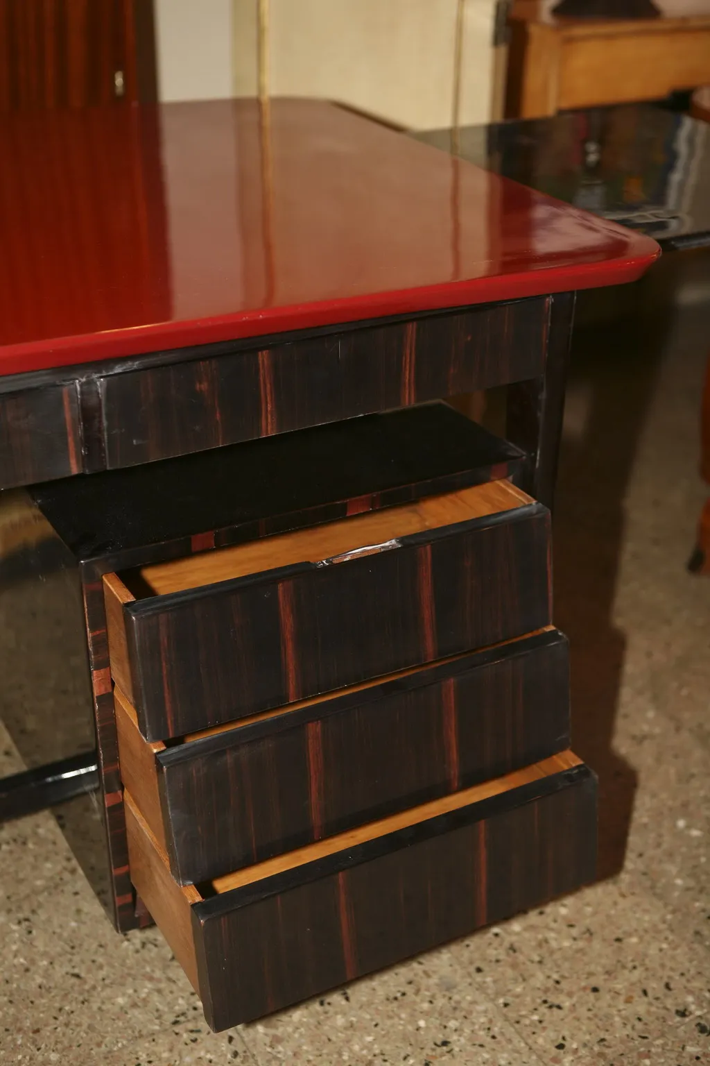 antiker Schreibtisch mit roter Oberfläche und drei Schubladen