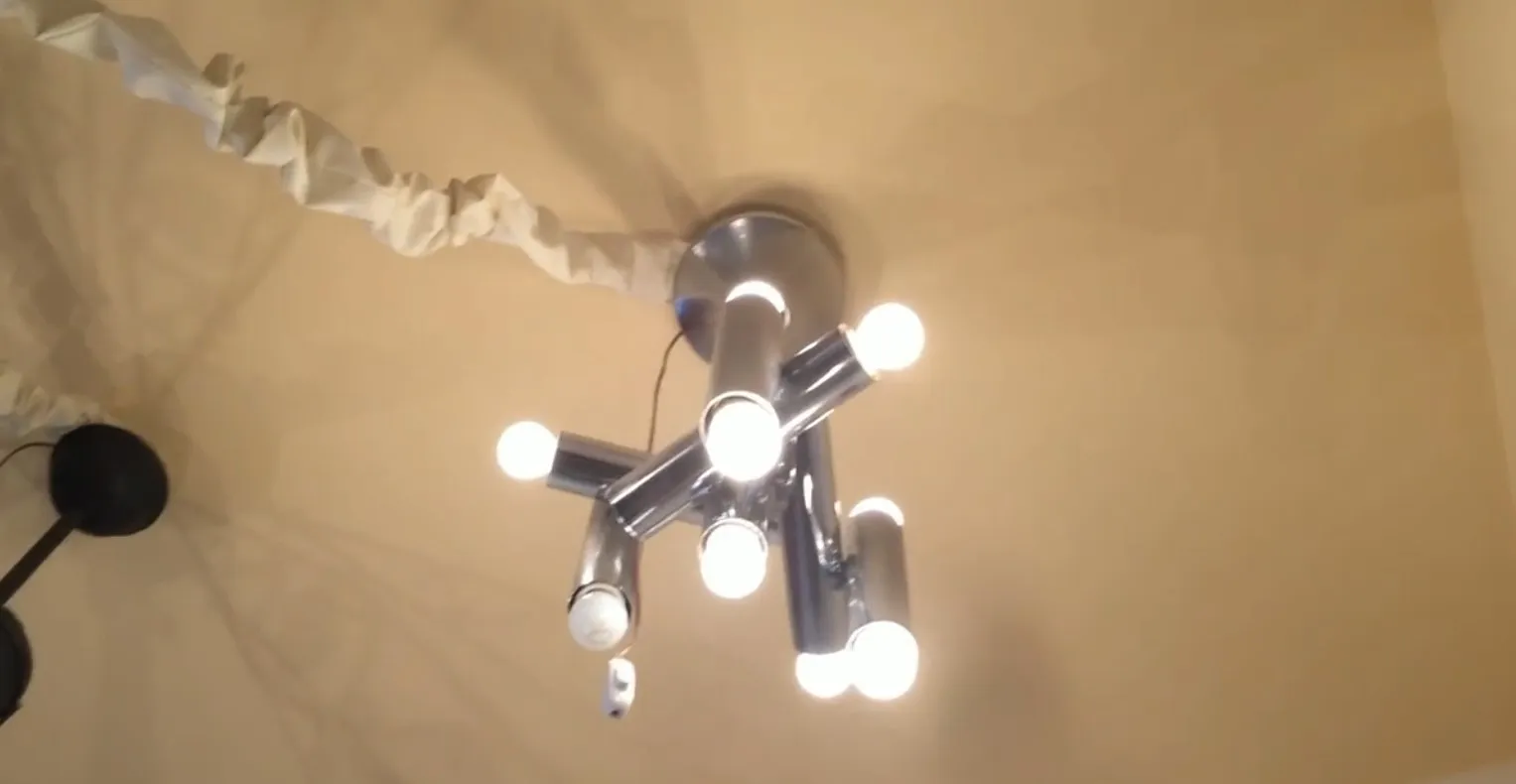 مصباح معلق قديم مع عدة أذرع وأضواء ساطعة في بيئة مريحة.