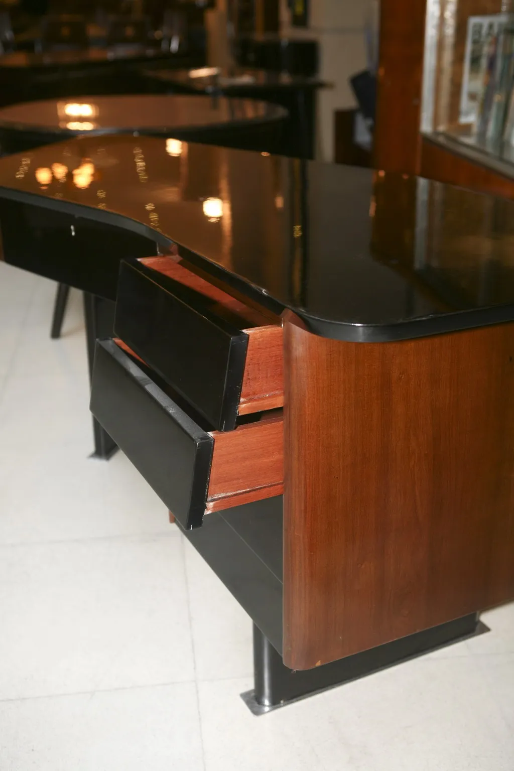 Vue latérale d'un bureau ancien avec finition noire et bois, comportant deux tiroirs