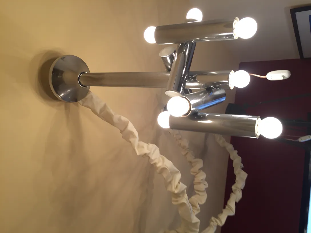 Lâmpada de teto antiga com várias lâmpadas brilhantes, em um ambiente iluminado.