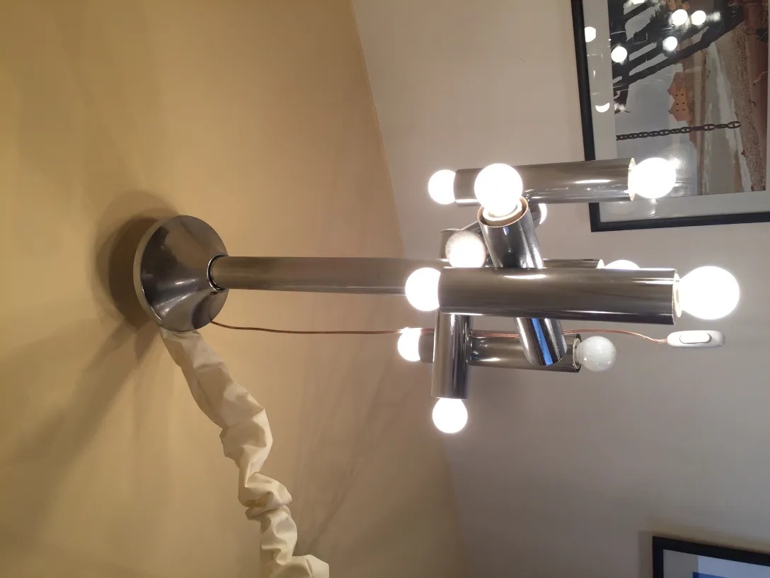 Lámpara de techo antigua con múltiples luces brillantes en un diseño moderno, sobre fondo claro.