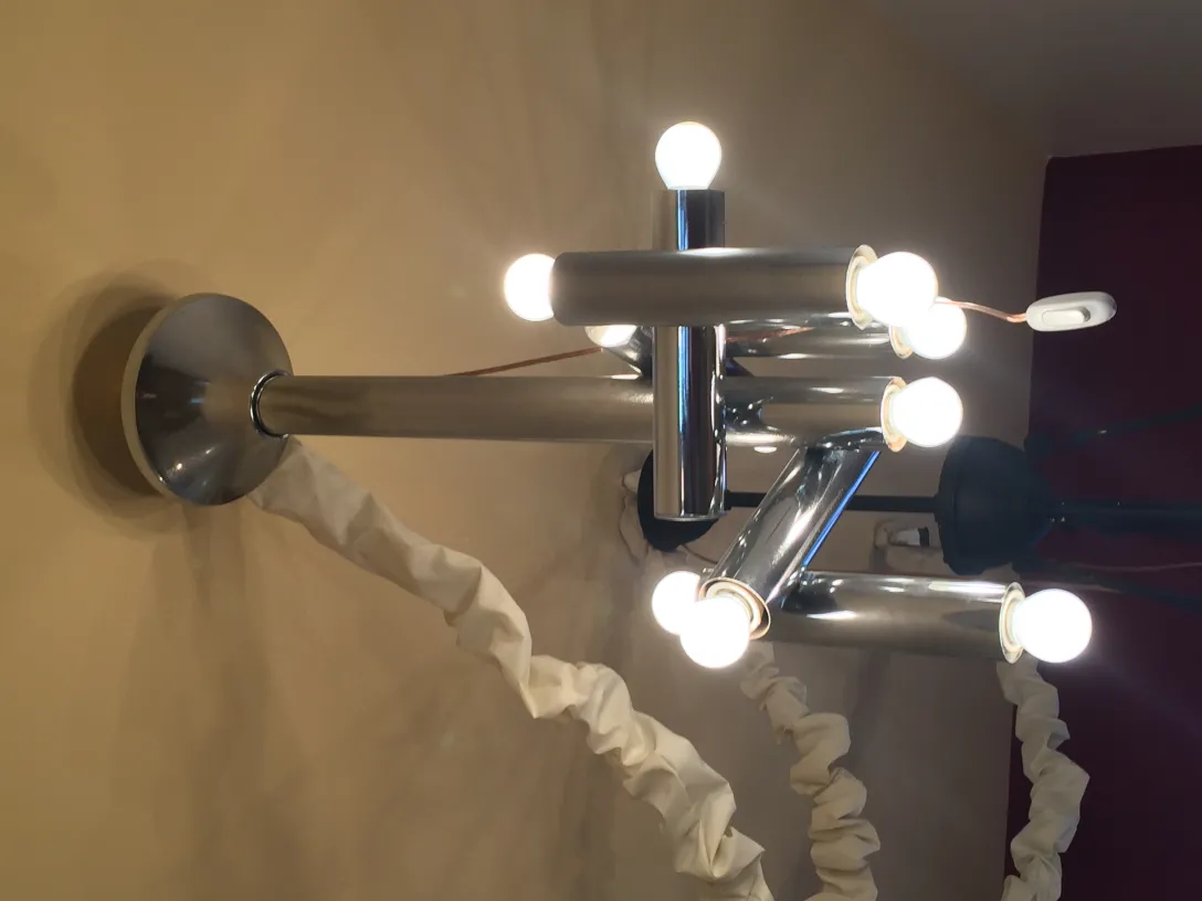 Lámpara de techo antigua con múltiples focos sobre pared clara.