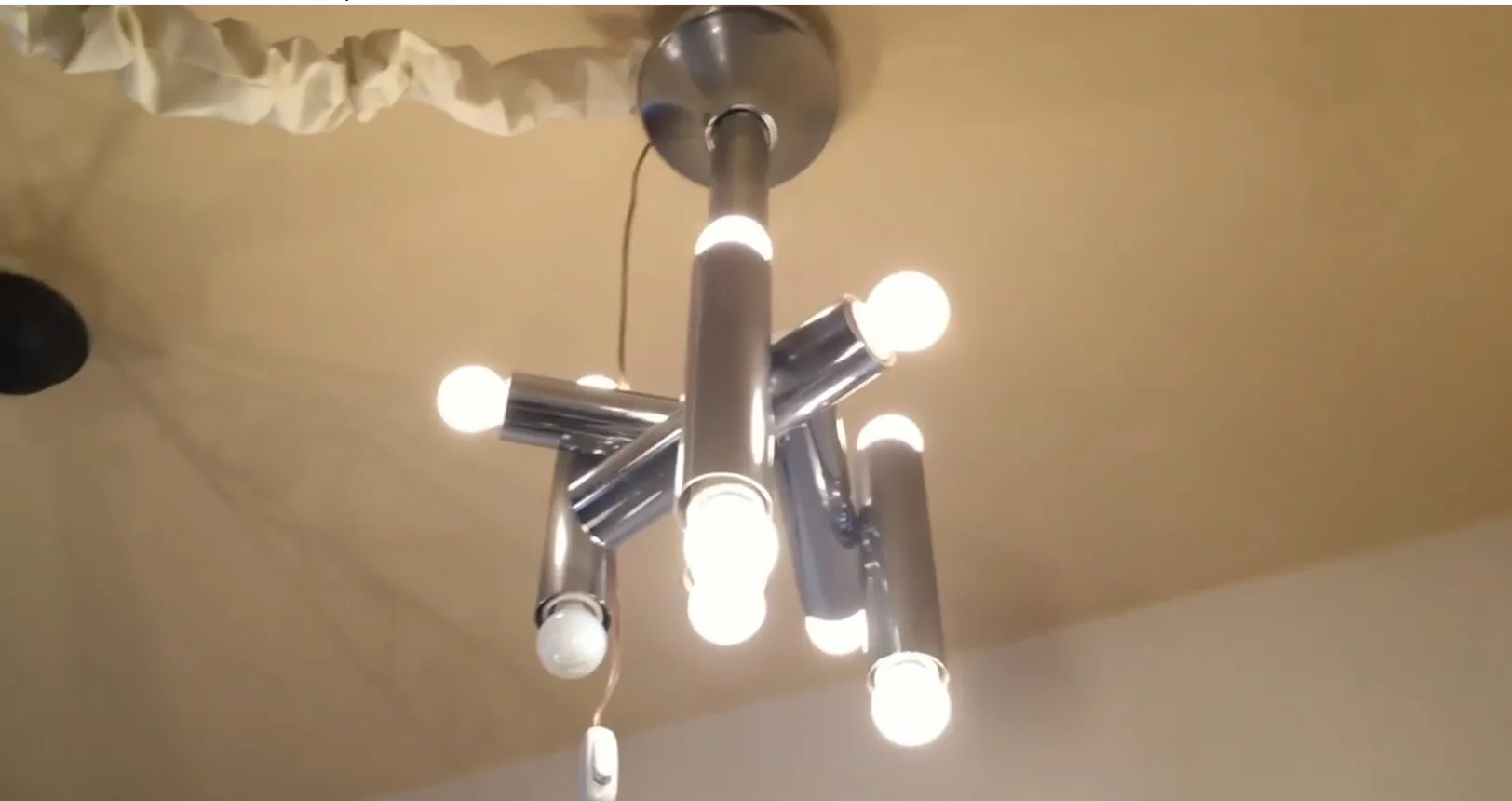 Lustre ancien en métal avec plusieurs globes lumineux, dans un cadre moderne.