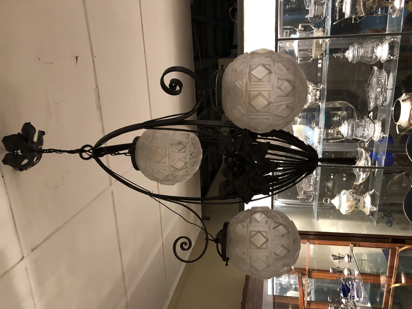 Lustre ancien avec trois sphères en verre blanc dans un cadre élégant.