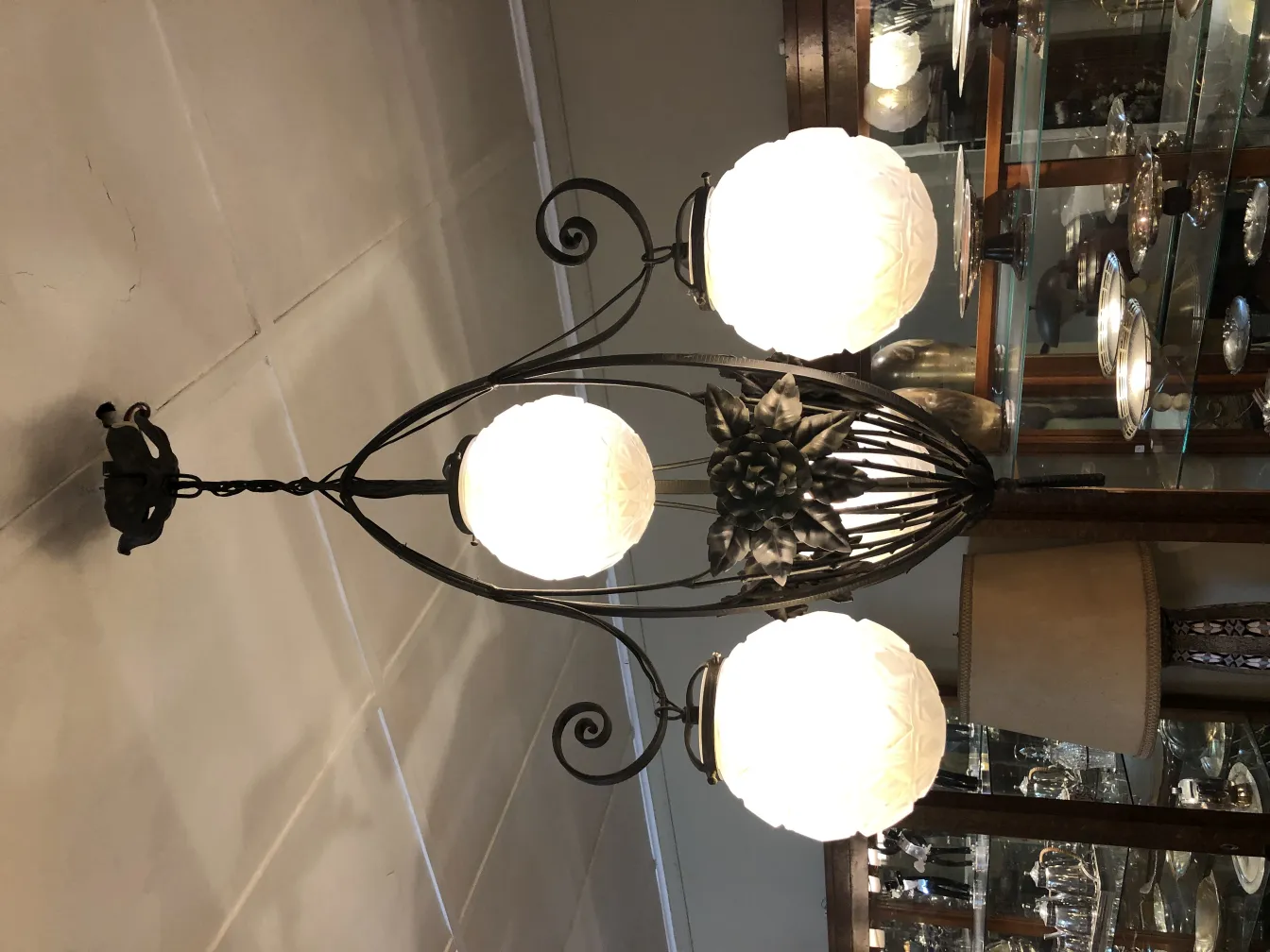 Lustre ancien avec trois globes en verre dans un environnement élégant.