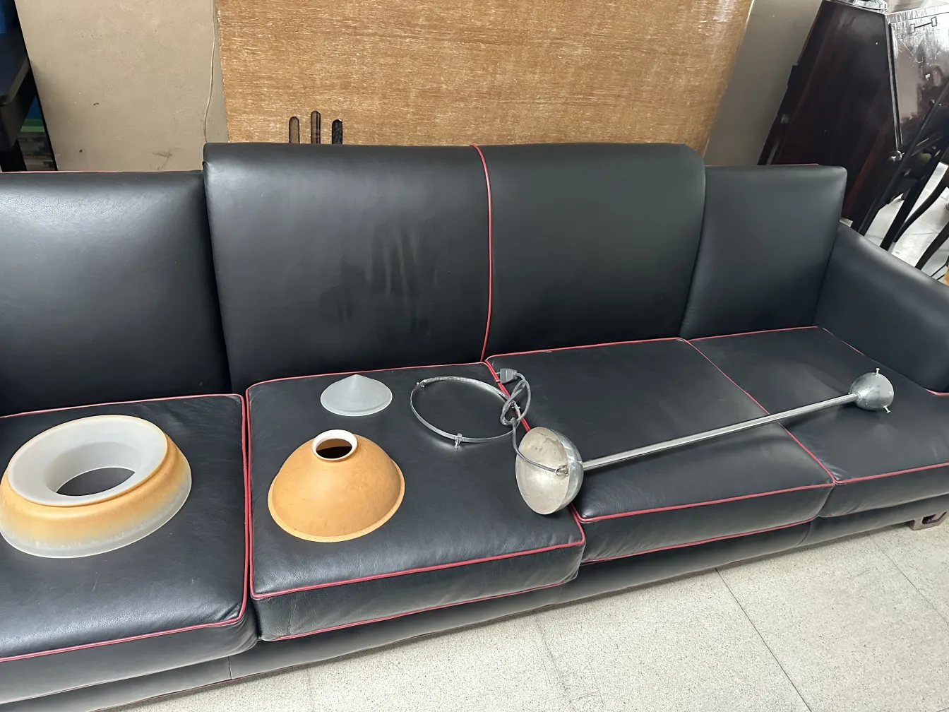 Antique hanging lamp laid out on a sofa, with visible parts and a cluttered background.