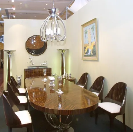 Lámpara de techo antigua con múltiples brazos y estilo elegante, en un ambiente moderno con mesa y sillas.